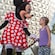 Minnie holds hands and shares a laugh with a little girl in front of Spaceship Earth